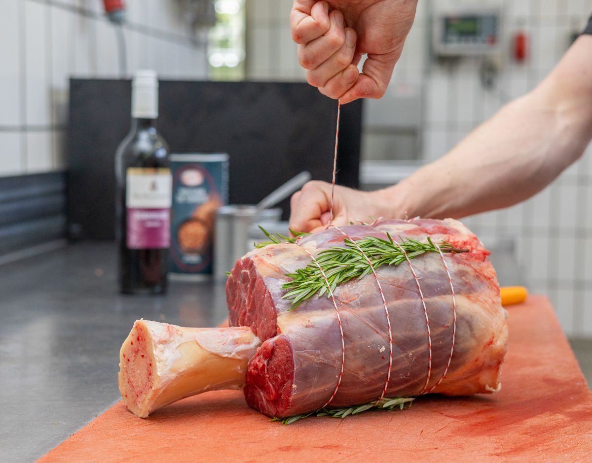 Eine Person schneidet ein Stück Fleisch auf einem Schneidebrett.