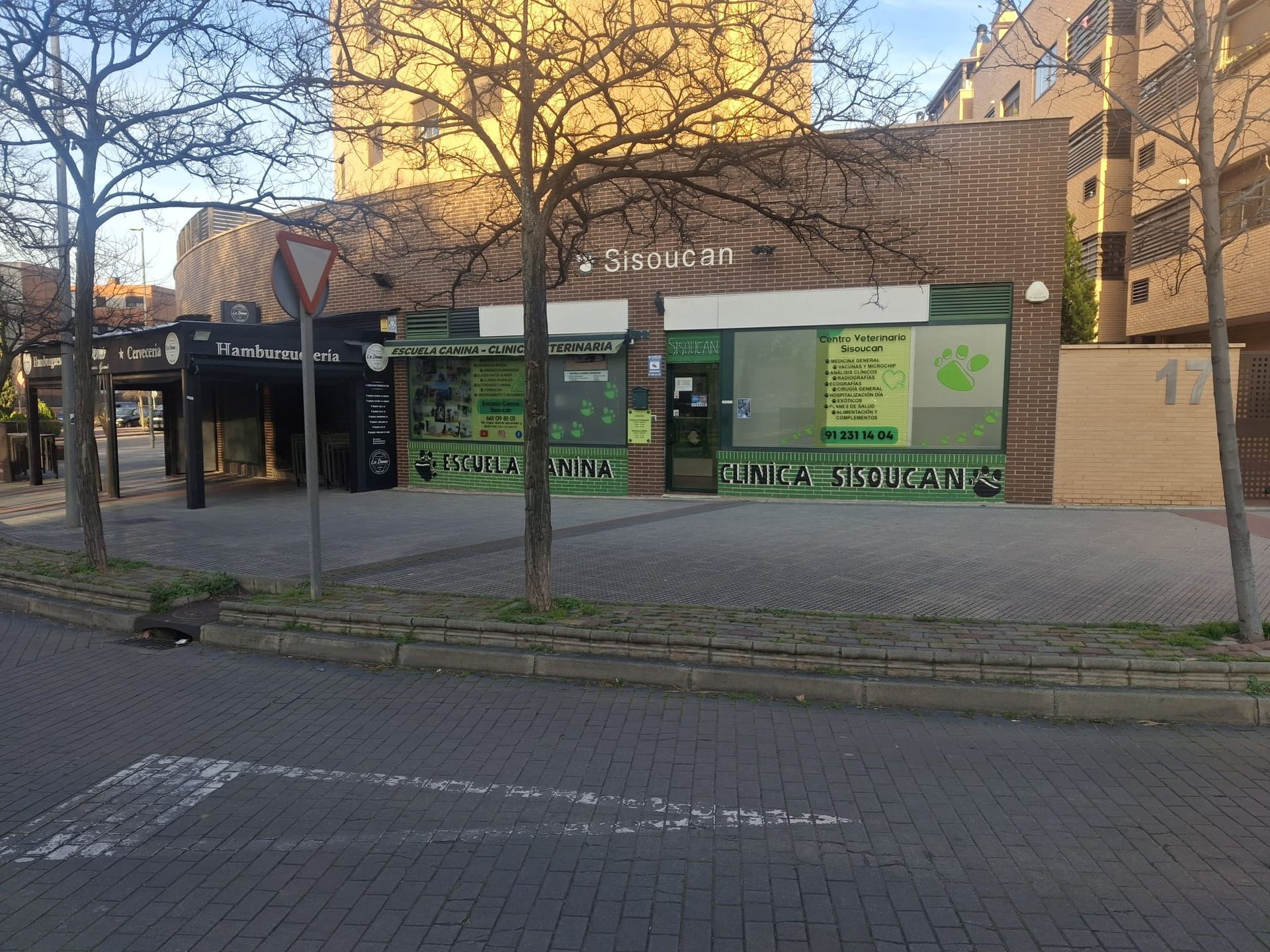 Una tienda de artículos para mascotas con una fachada verde y una zona de estar exterior cubierta.