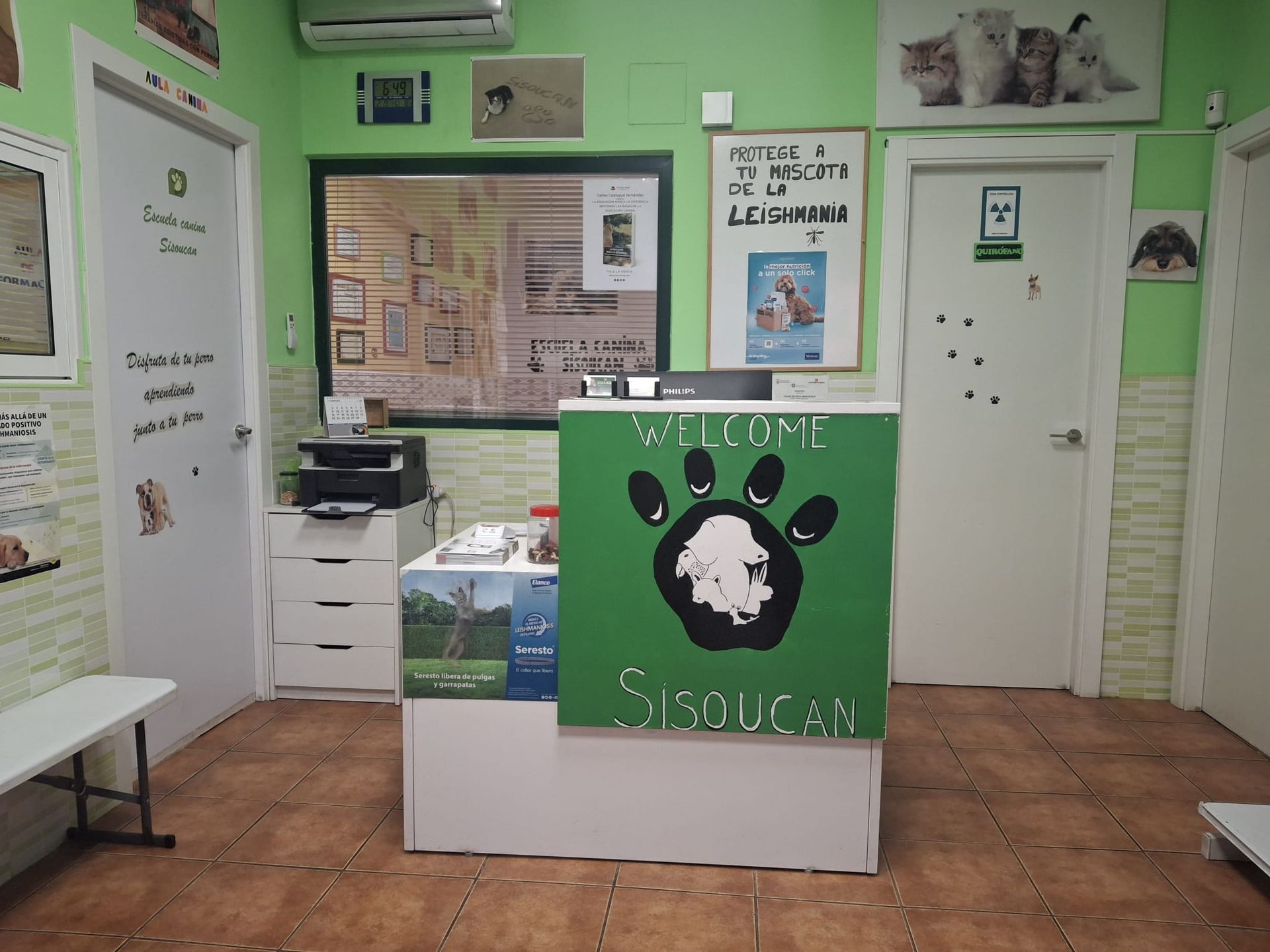 Área de recepción de la clínica veterinaria con un mostrador frontal de color verde y el logotipo de la huella de una pata.