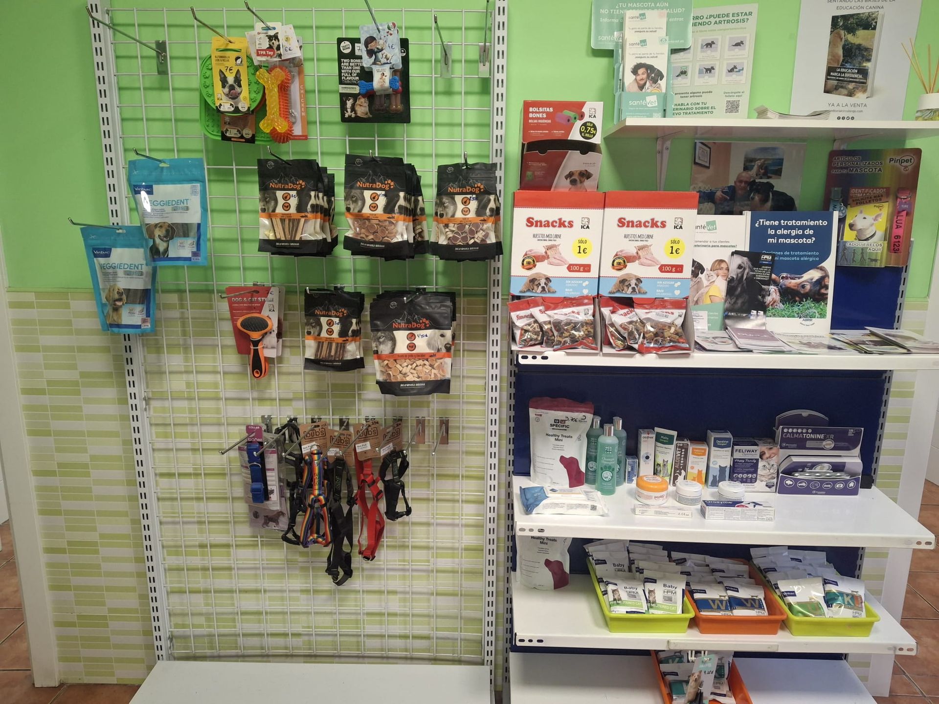 Exhibidores de comida y golosinas para perros en una tienda de mascotas, con productos colgantes y exhibidores en estantes.