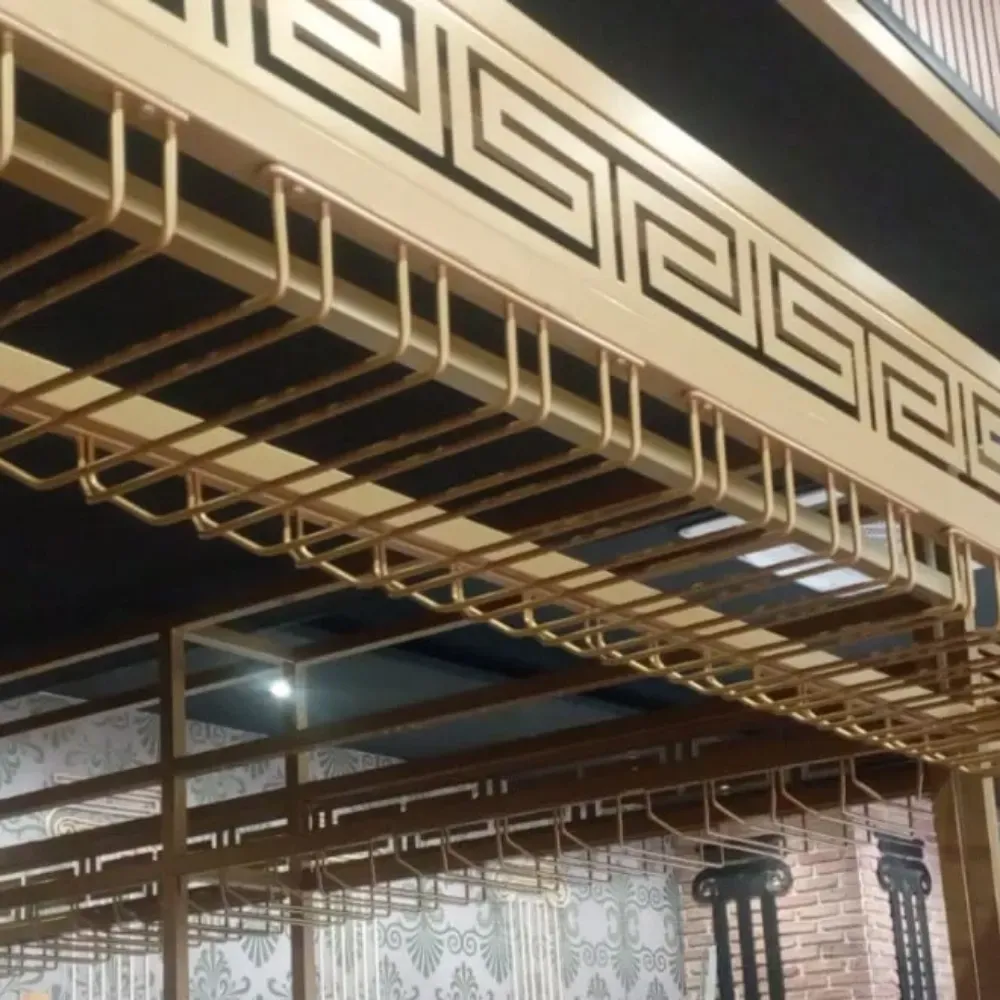 Barandilla decorativa de metal para balcón con diseño de greca y barras colgantes bajo un techo por la noche.