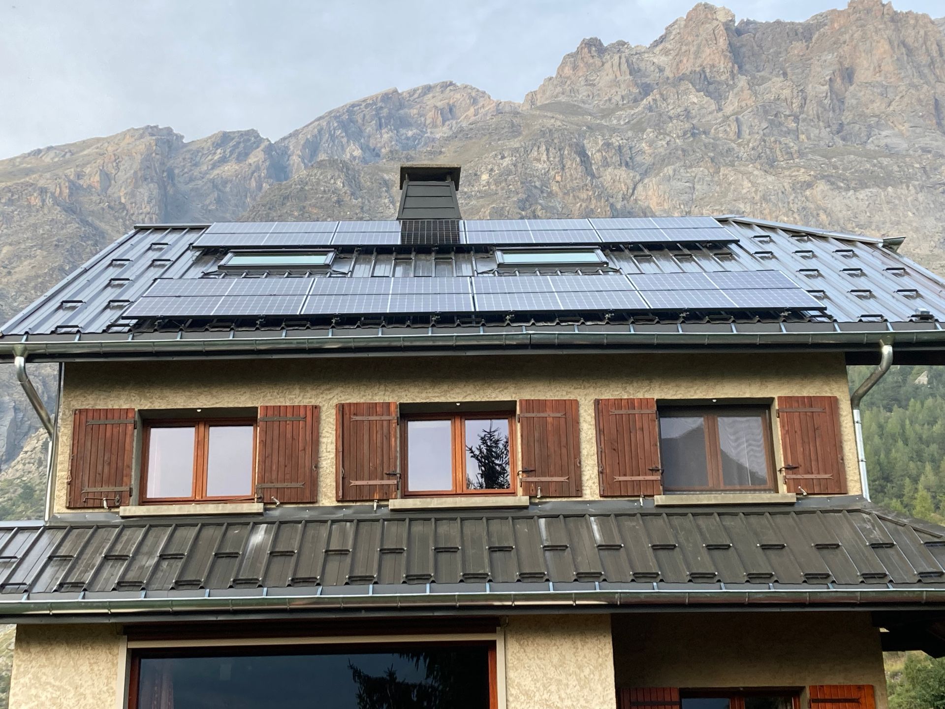 Une maison à la toiture en zinc disposant de panneaux solaires sur le toit