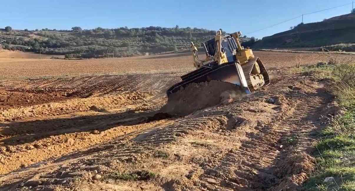 Zanjas excavadas en un terreno despejado con suelo removido y árboles al fondo.