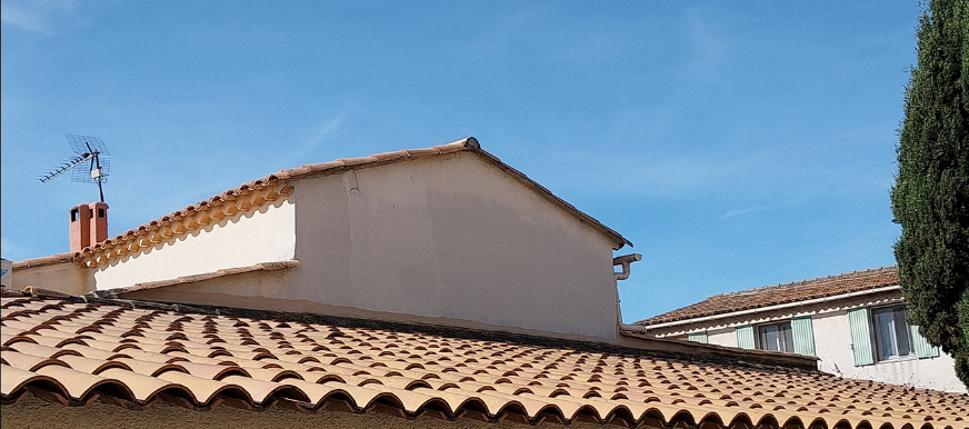 Une maison avec un toit de tuiles et une antenne au-dessus.