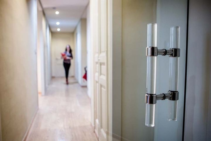 Couloir avec une personne floue marchant au loin et une poignée de porte en verre au premier plan