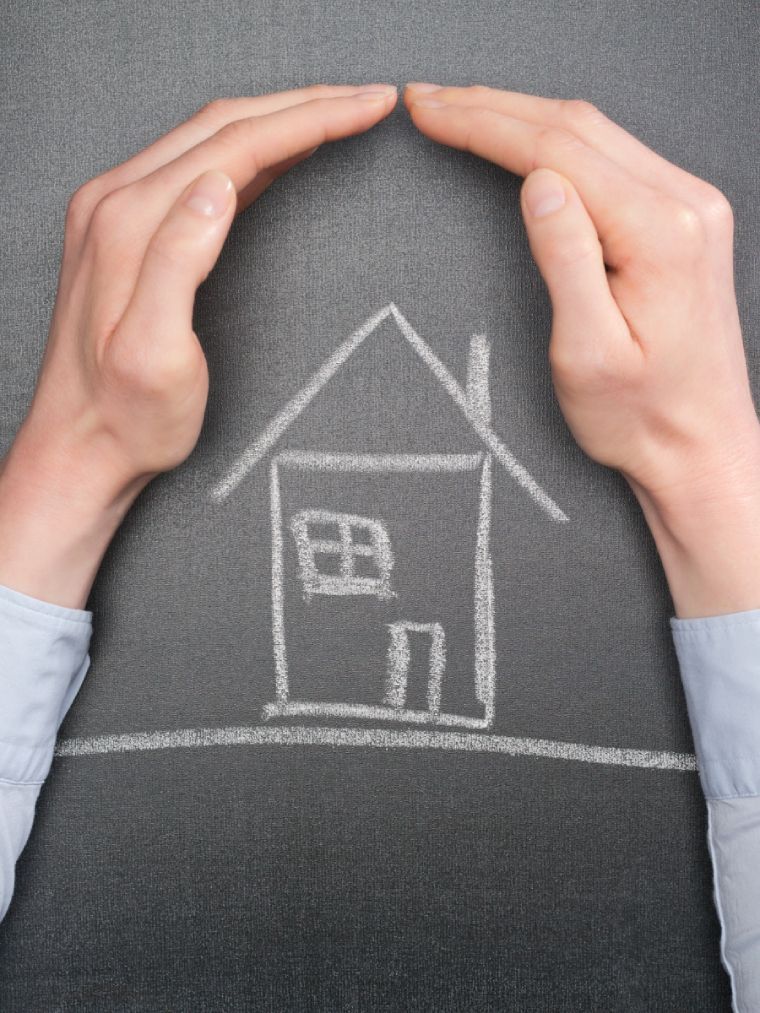 Des mains encadrent une maison dessinée à la craie sur un fond sombre.