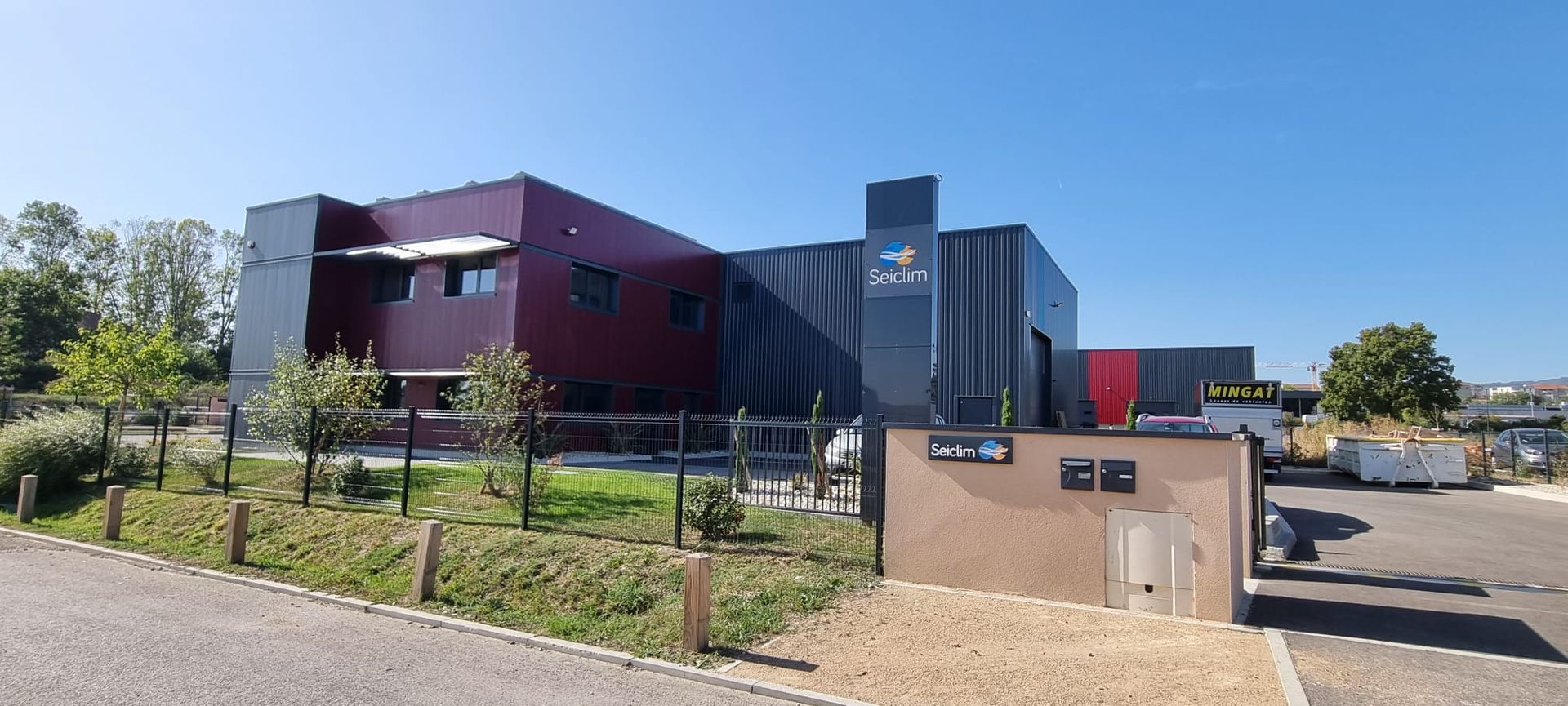 Bâtiment industriel moderne à l'extérieur rouge et noir, sous un soleil radieux. SEICLIM