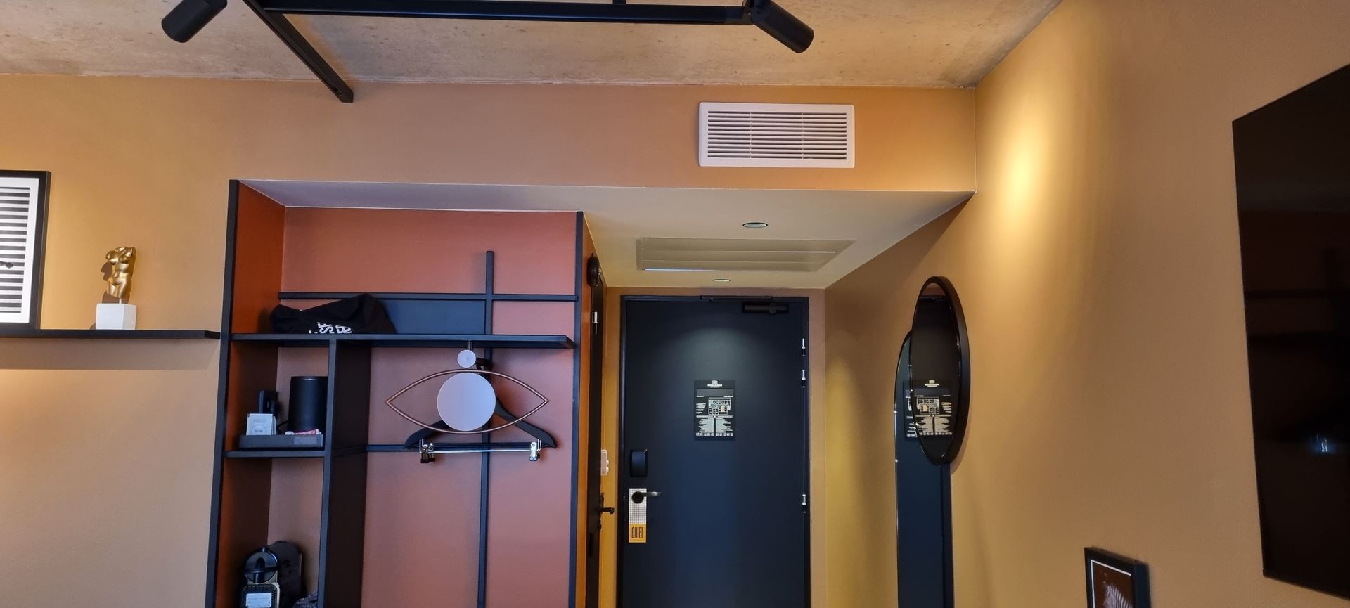 Intérieur d'une chambre d'hôtel avec des murs marrons, une armoire et une porte.