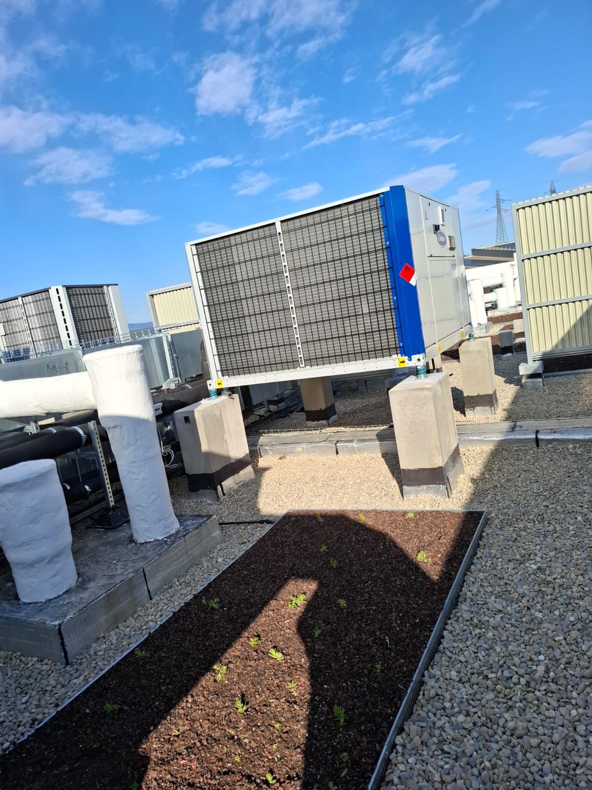 Toiture avec unités de climatisation sur blocs de béton ; ciel bleu en arrière-plan.