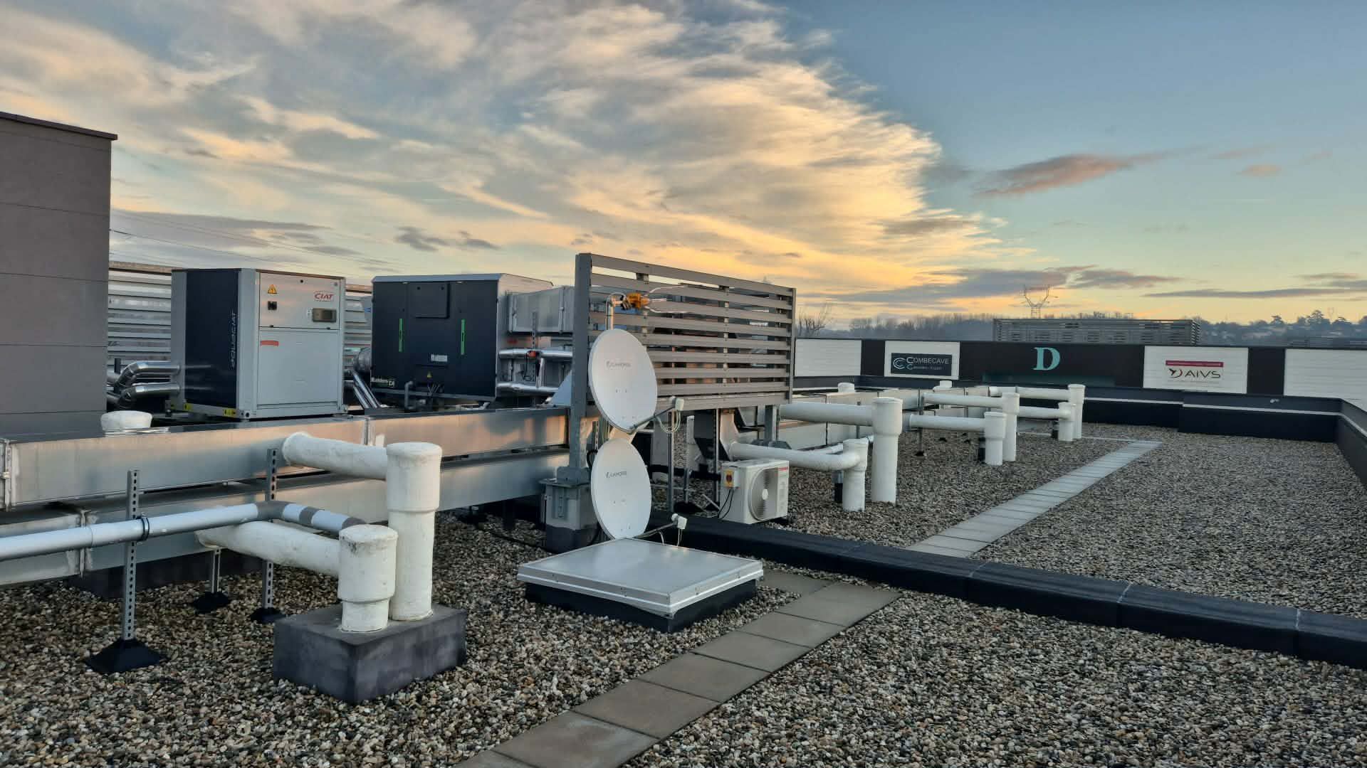 Toit avec équipements de communication, canalisations et surface en pierre. 