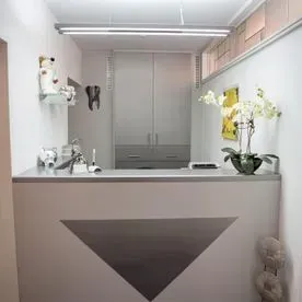 Moderner, minimalistischer Empfangstresen mit weißen Orchideen in einer kleinen Klinik- oder Spa-Lobby