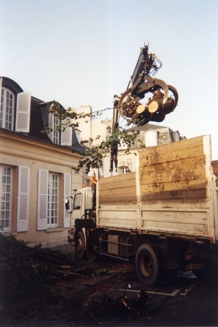 Camion-grue soulevant des débris à côté d'une maison avec des lucarnes