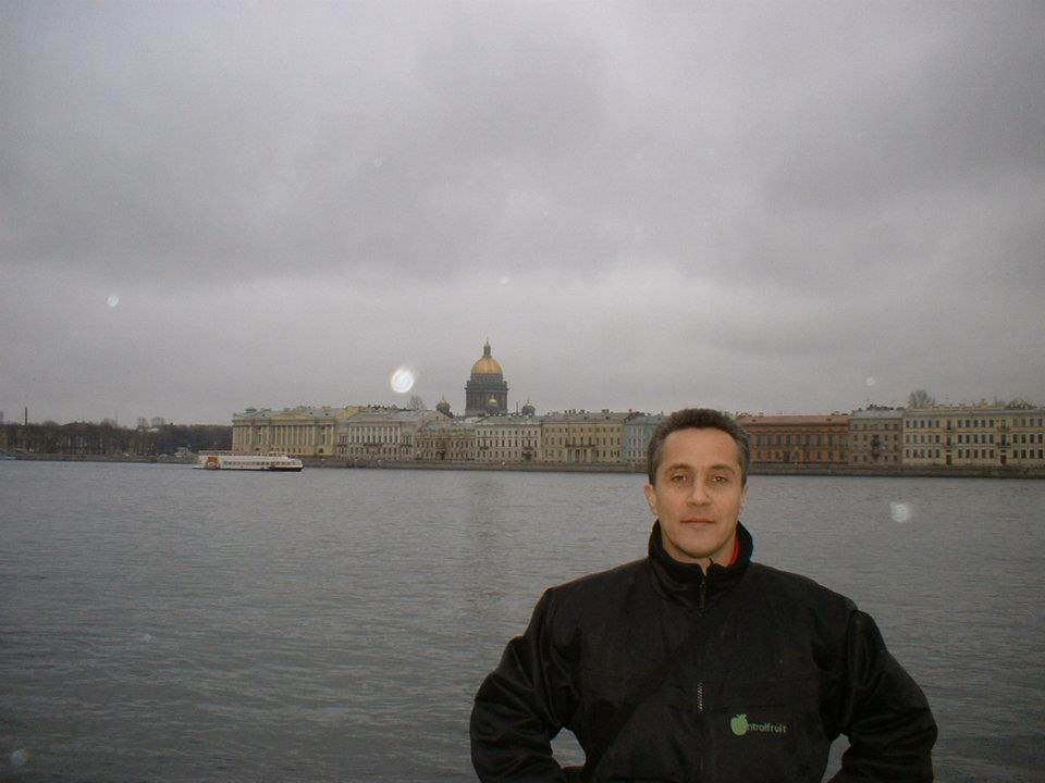 Un hombre con una chaqueta negra se encuentra frente a un cuerpo de agua.