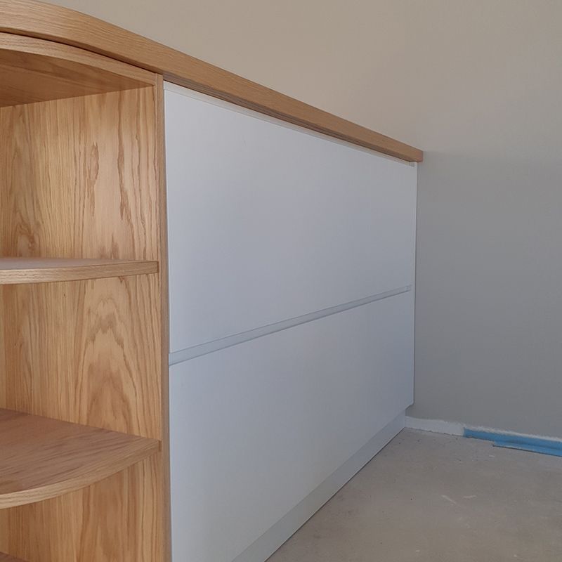Ein Holzregal neben einem weißen Schrank in einem Zimmer.