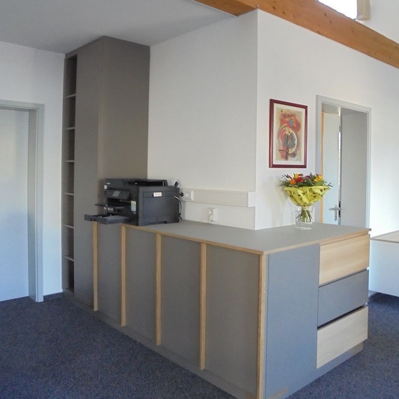 Ein Schreibtisch mit einem Drucker und einer Vase mit Blumen darauf