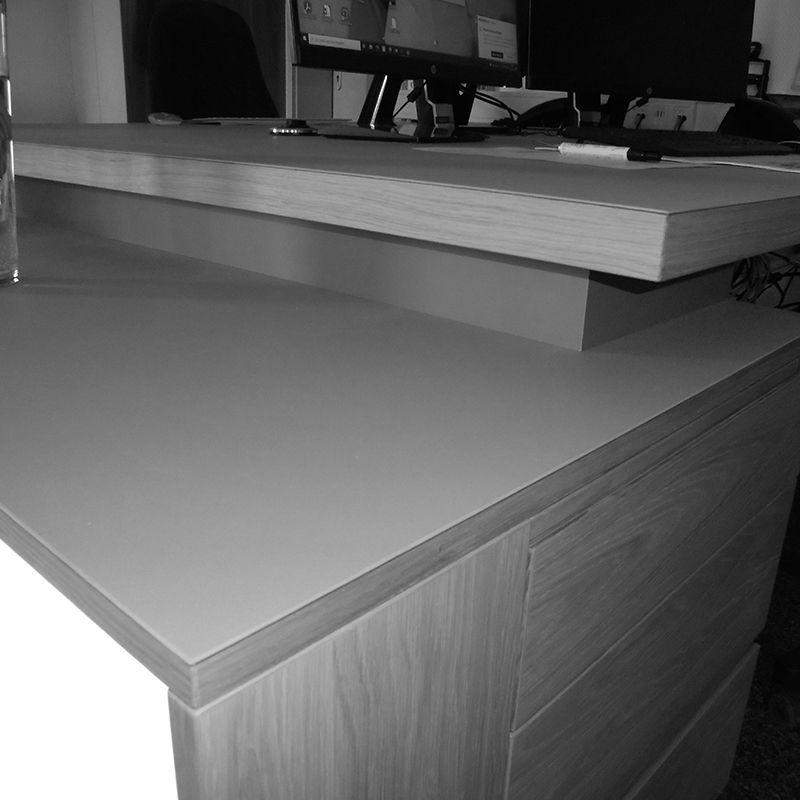 Ein Schwarzweißfoto eines Schreibtischs mit einem Computer darauf.