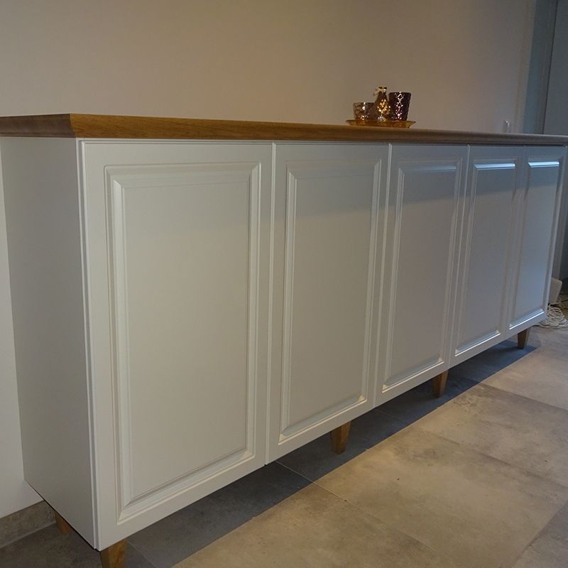 Ein weißer Schrank mit Holzplatte steht auf einem gefliesten Boden.