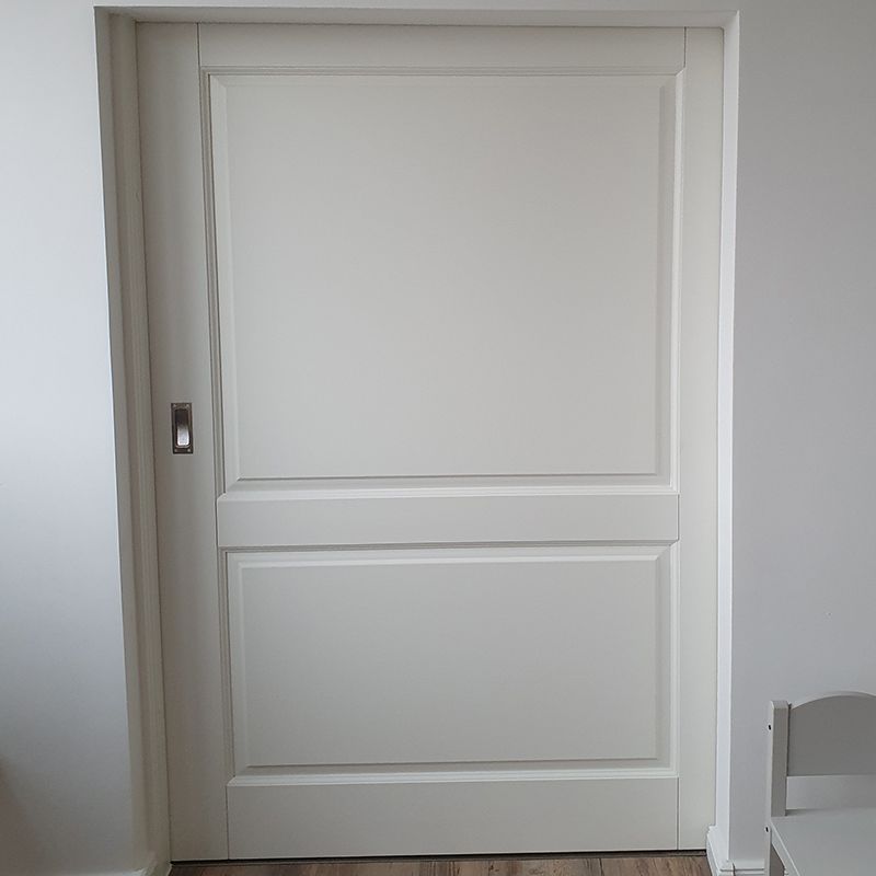 In einem Raum neben einem Stuhl steht eine weiße Tür.