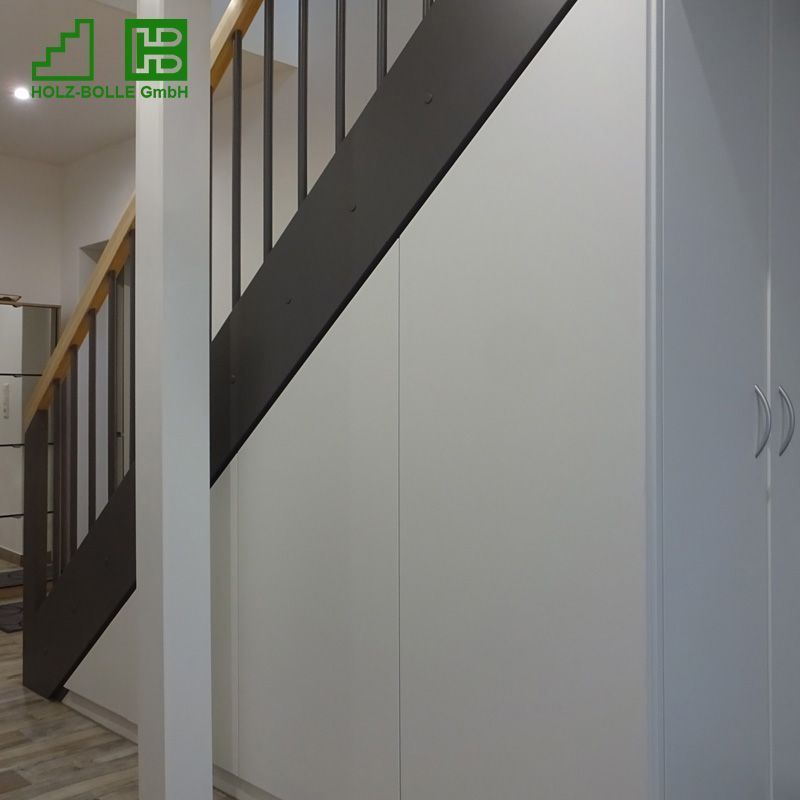 Eine Treppe mit schwarzem Geländer und weißen Schränken darunter.