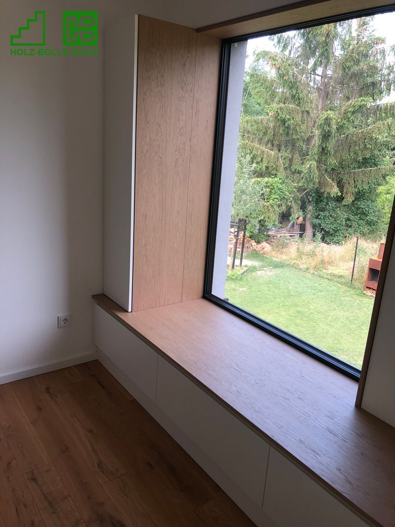 Ein Raum mit einem großen Fenster und einer Holzbank davor.