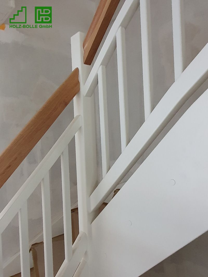 Eine Treppe mit einem weißen Geländer und einem Holzhandlauf