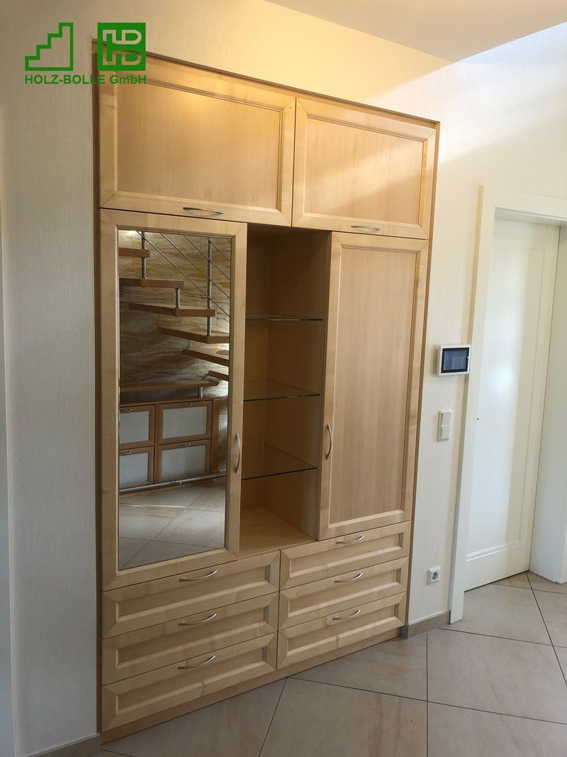 Ein Holzschrank mit Schubladen und einem Spiegel in einem Flur