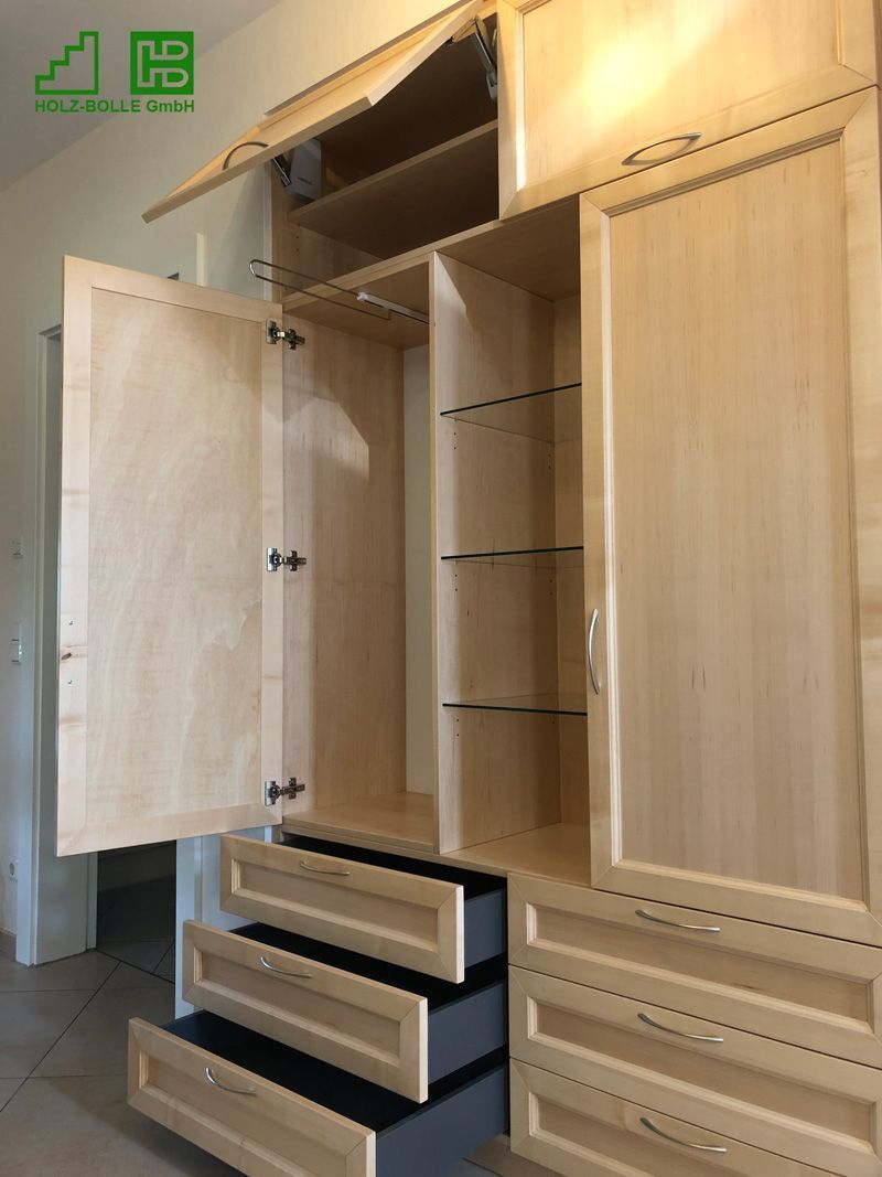 Ein Holzkleiderschrank mit offenen Türen und Schubladen.