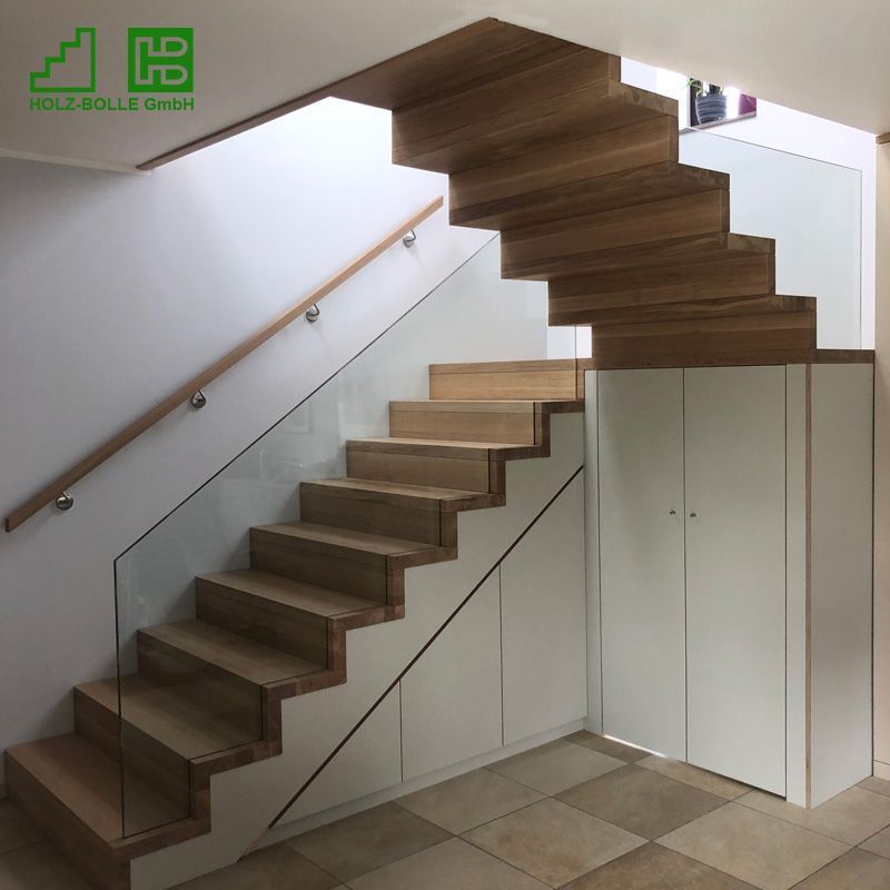 Eine Holztreppe mit einem Glasgeländer in einem Raum.