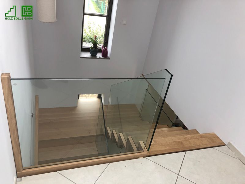 Eine Holztreppe mit Glasgeländer und Fenster.