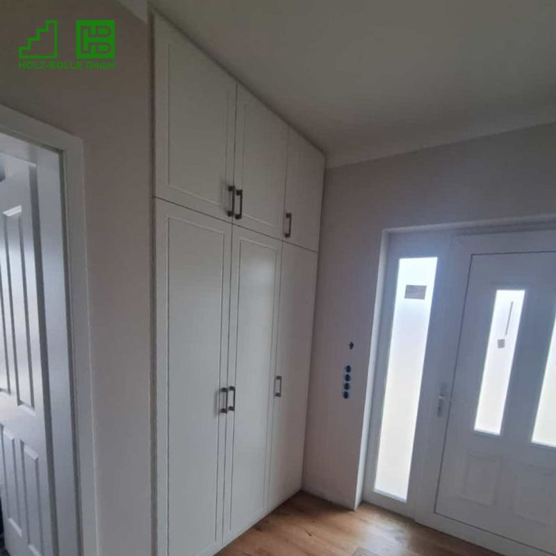 Ein Flur mit weißen Schränken und einer Tür.