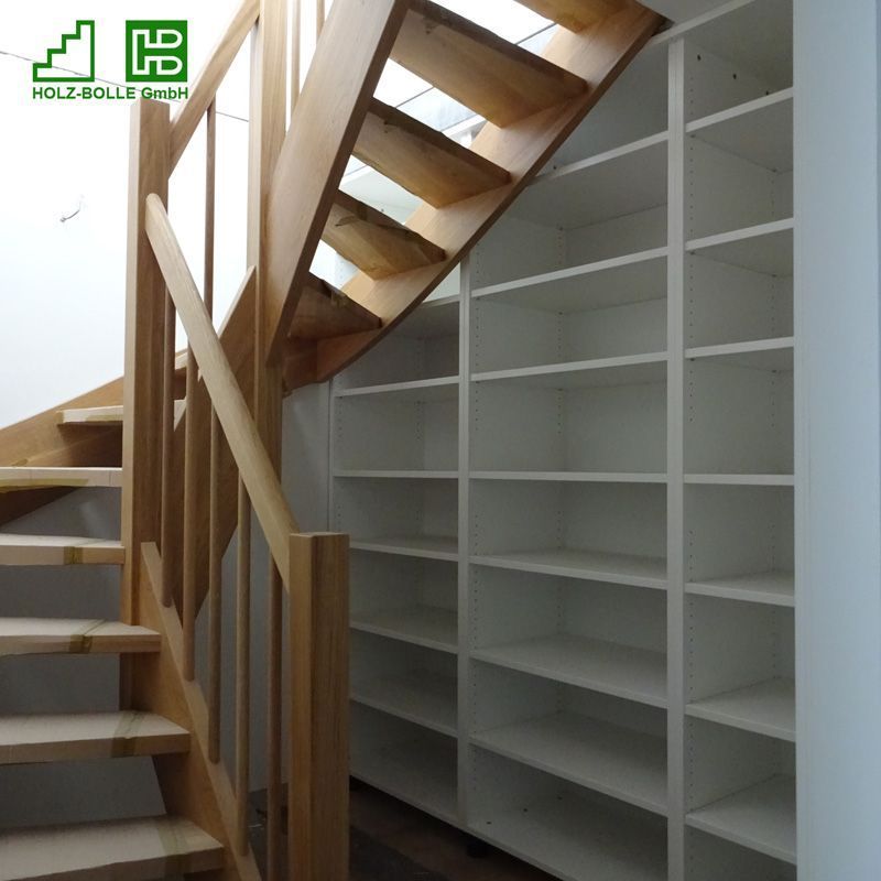 Eine Holztreppe, die zu einer Wand mit weißen Regalen führt