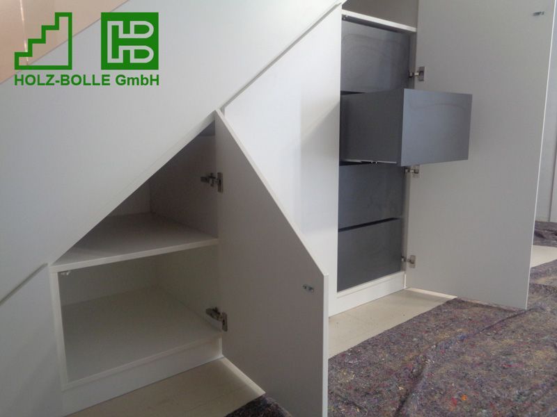 Ein weißer Schrank unter einer Treppe mit Schubladen und Regalen
