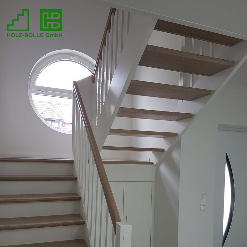 Eine weiße Treppe mit Holzstufen und einem runden Fenster