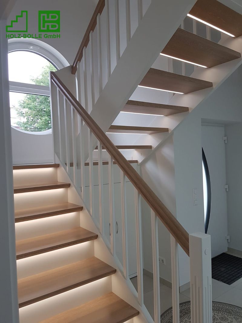 Eine Holztreppe mit weißem Geländer und Lichtern auf den Stufen.