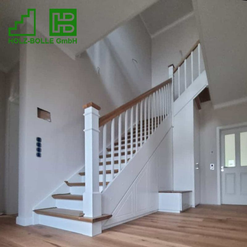 Eine weiße Treppe mit einem Holzgeländer in einem Flur