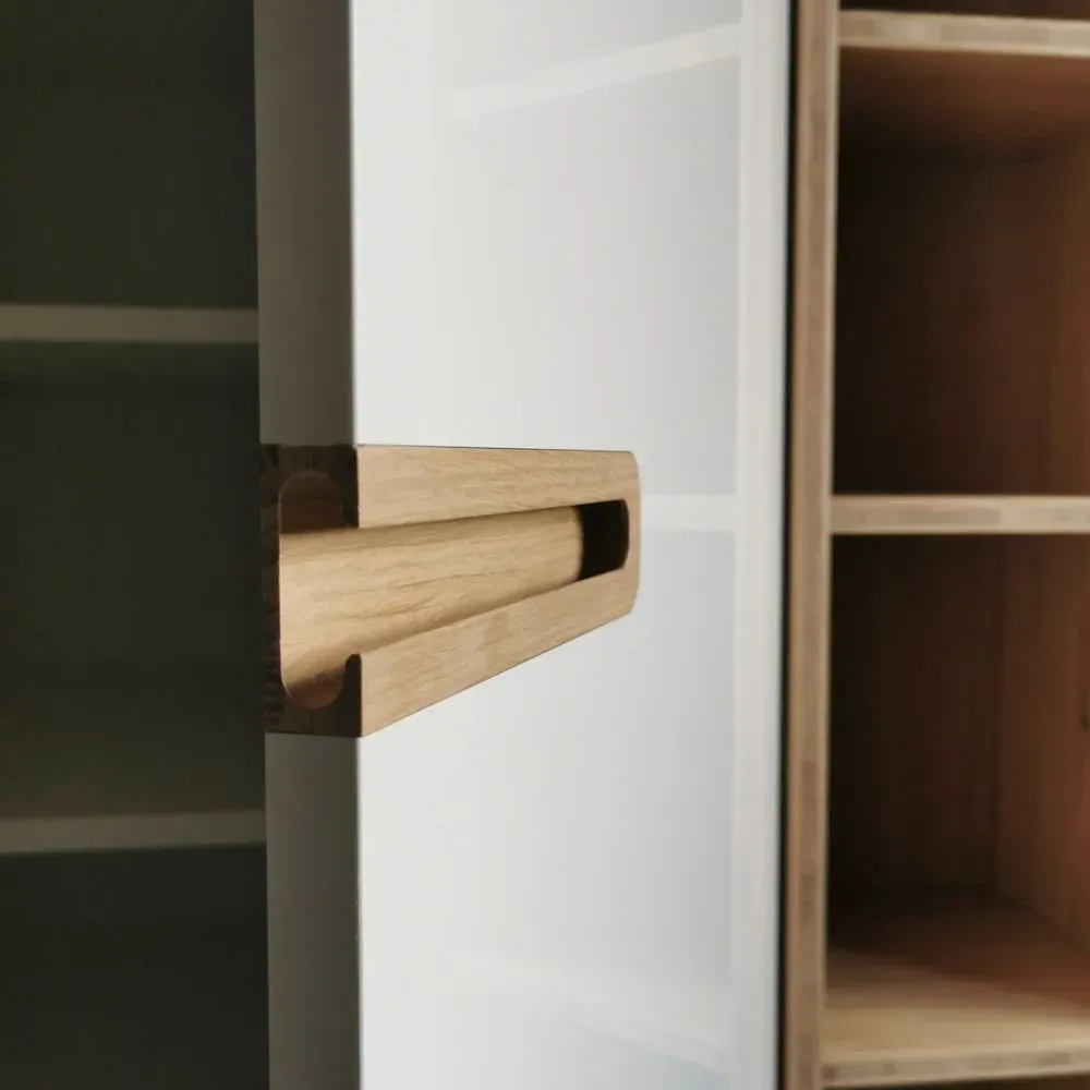 Eine Nahaufnahme von einem Holzgriff auf einem weißen Schrank