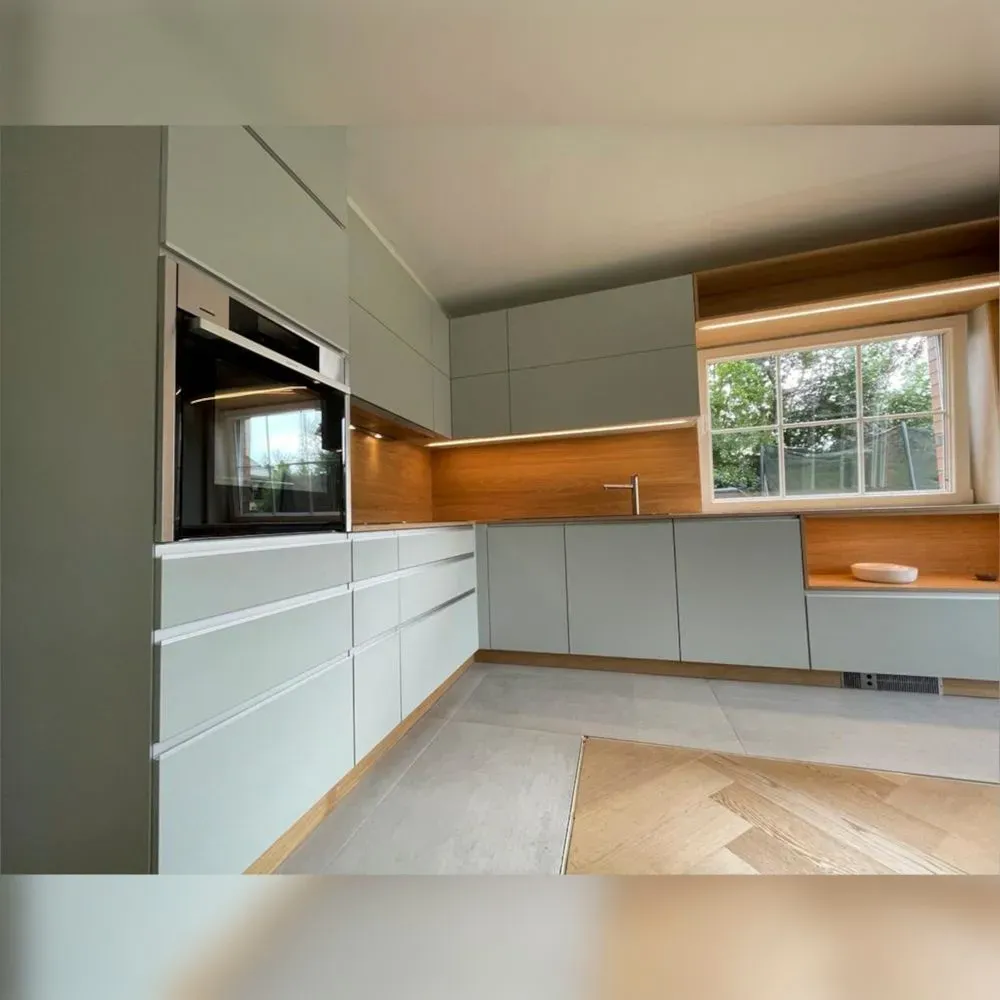 Eine Küche mit weißen Schränken und einem großen Fenster