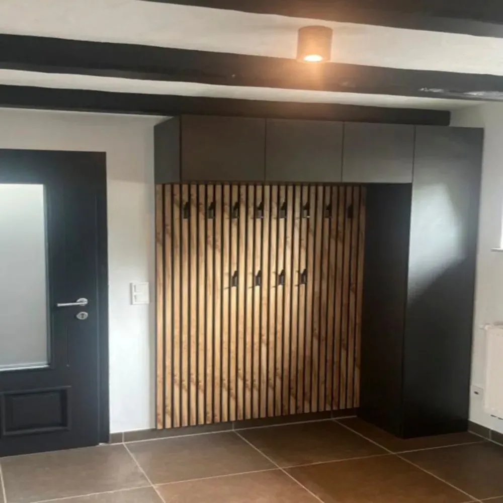 Ein Raum mit einer Holzwand und einer schwarzen Tür.