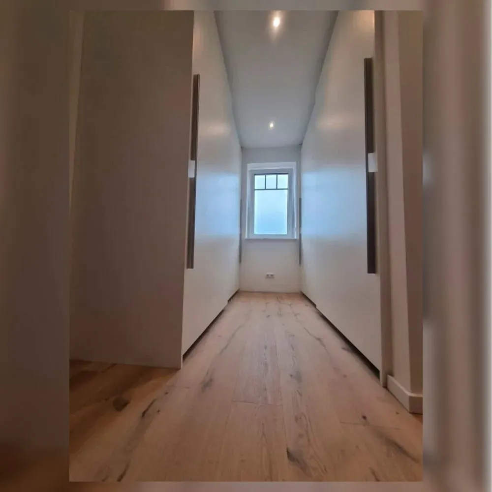 Ein langer Flur mit Holzboden und weißen Wänden