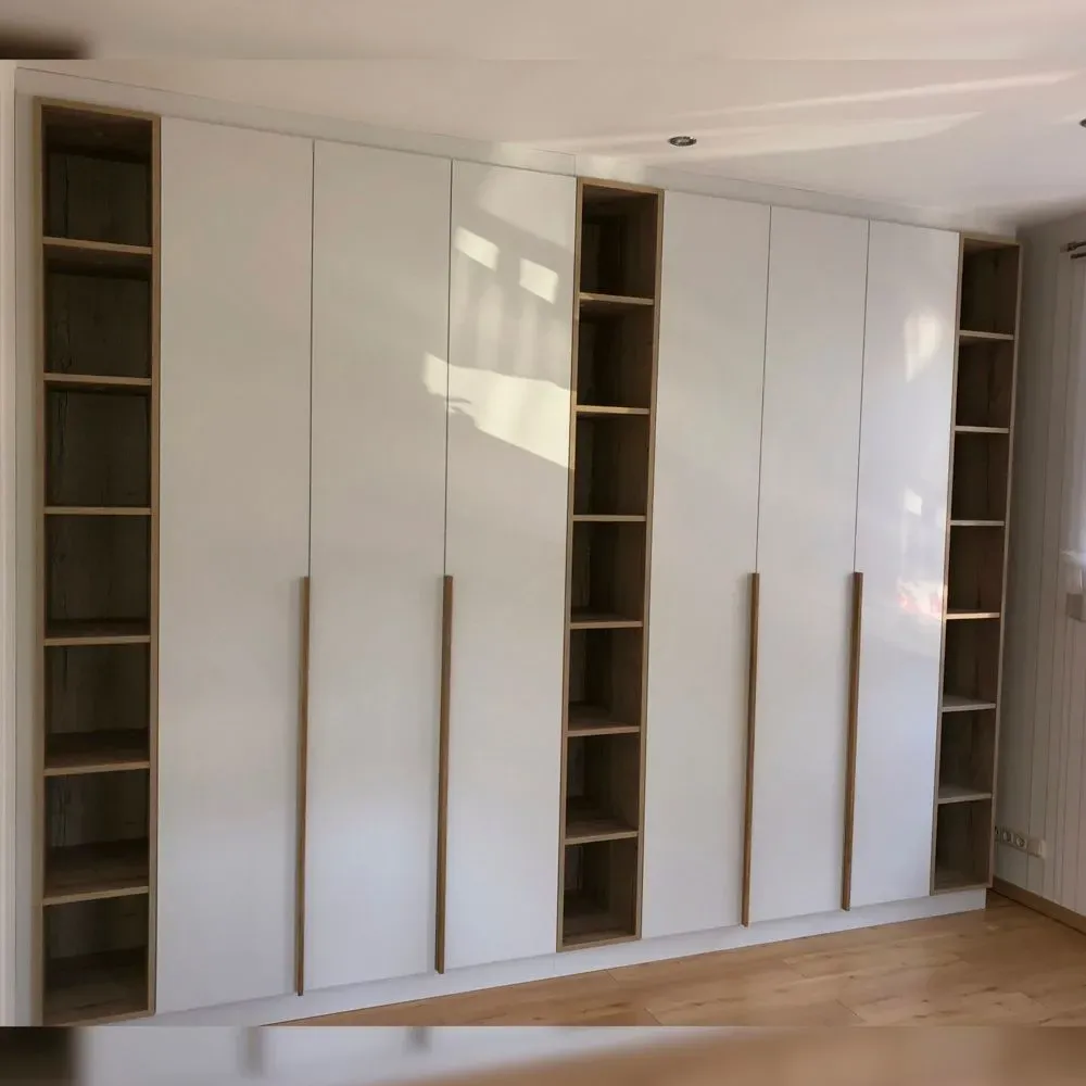 Eine Reihe weißer Schränke mit Holzregalen in einem Raum.