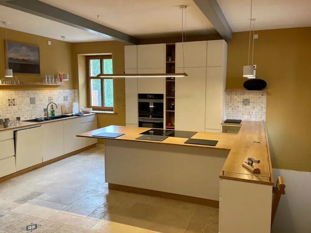 Eine Küche mit weißen Schränken und einer großen Insel in der Mitte.