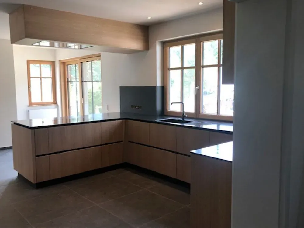 Eine Küche mit Holzschränken und schwarzen Arbeitsplatten