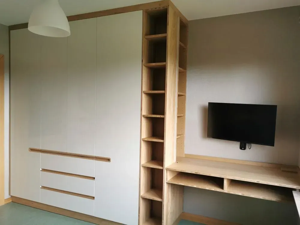 Ein Schlafzimmer mit Schreibtisch und Fernseher an der Wand