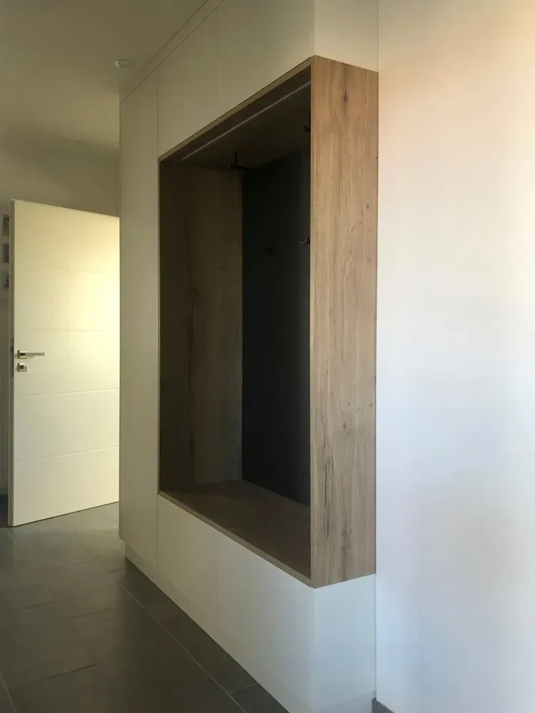 Ein Flur mit einem Holzregal und einer weißen Tür.