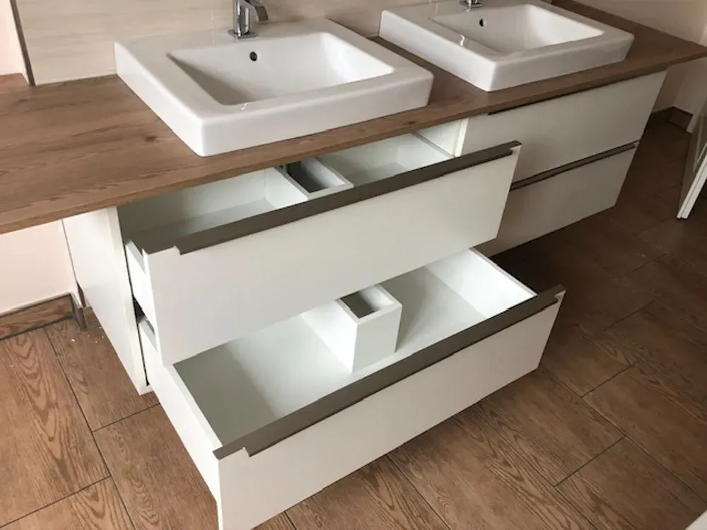 Ein Badezimmerschrank mit zwei Waschbecken und offenen Schubladen.