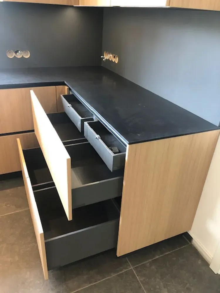 Eine Küche mit offenen Schubladen und einer schwarzen Arbeitsplatte