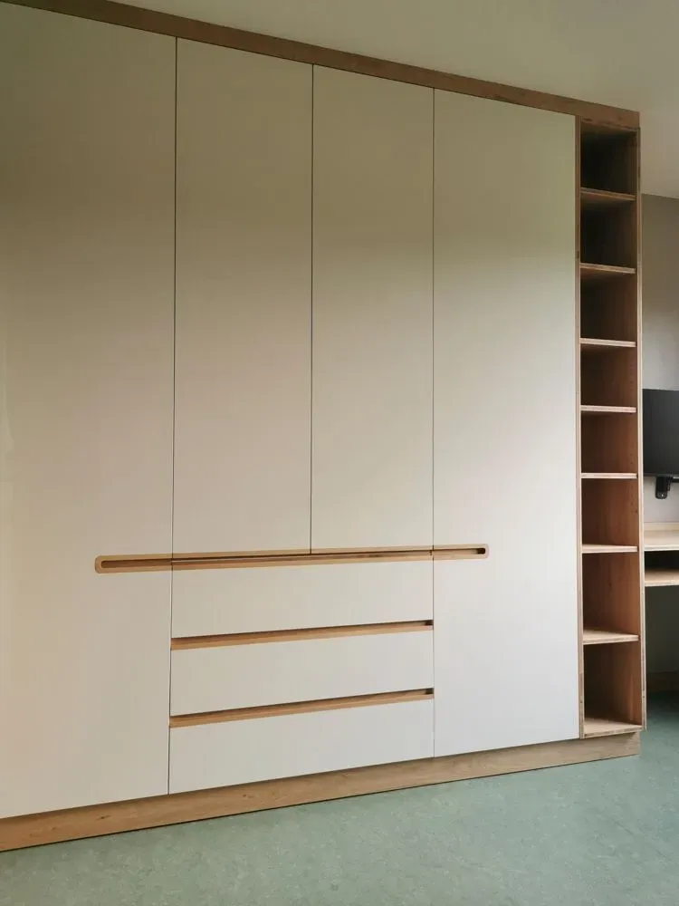 Ein Raum mit weißen Schränken und Holzregalen