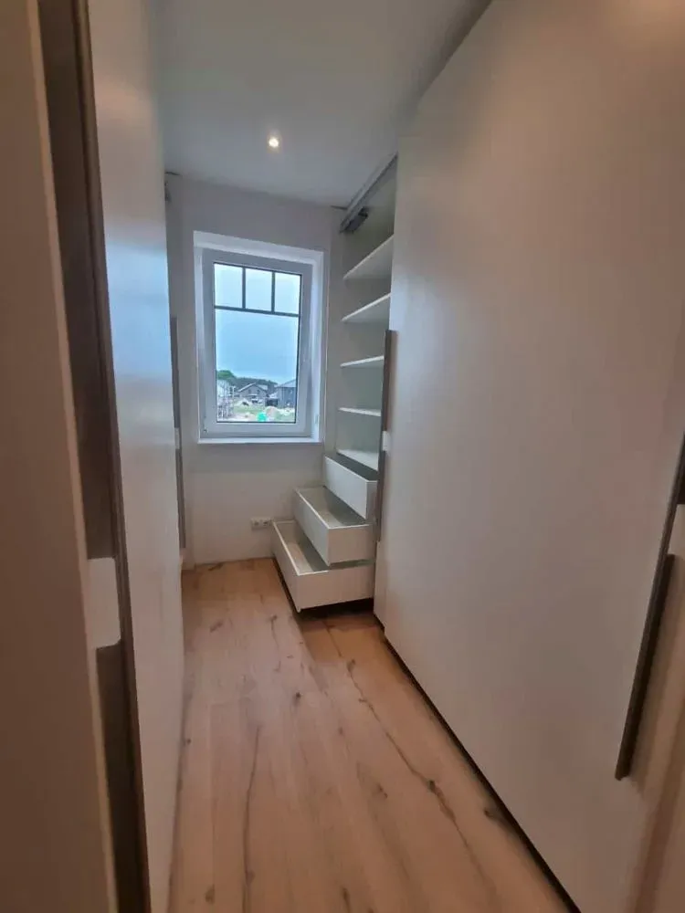 Ein begehbarer Kleiderschrank mit Schiebetüren und einem Fenster.