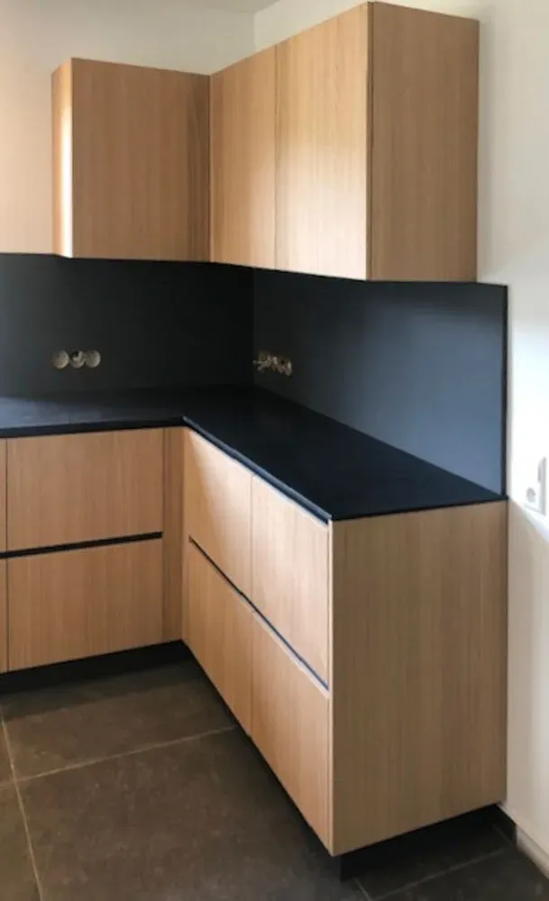 Eine Küche mit Holzschränken und einer schwarzen Arbeitsplatte