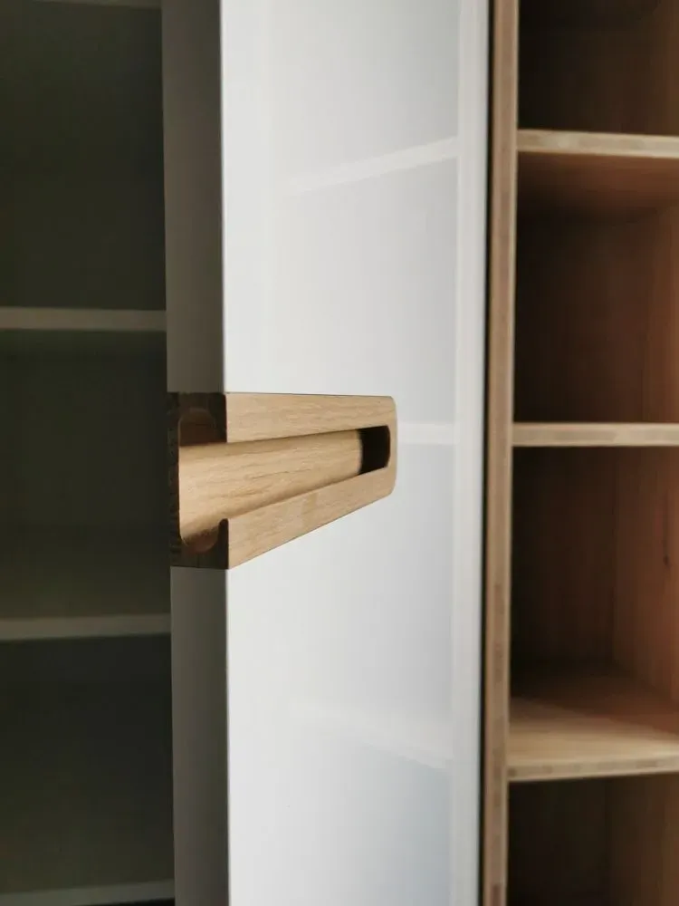 Eine Nahaufnahme von einem Holzgriff auf einem weißen Schrank